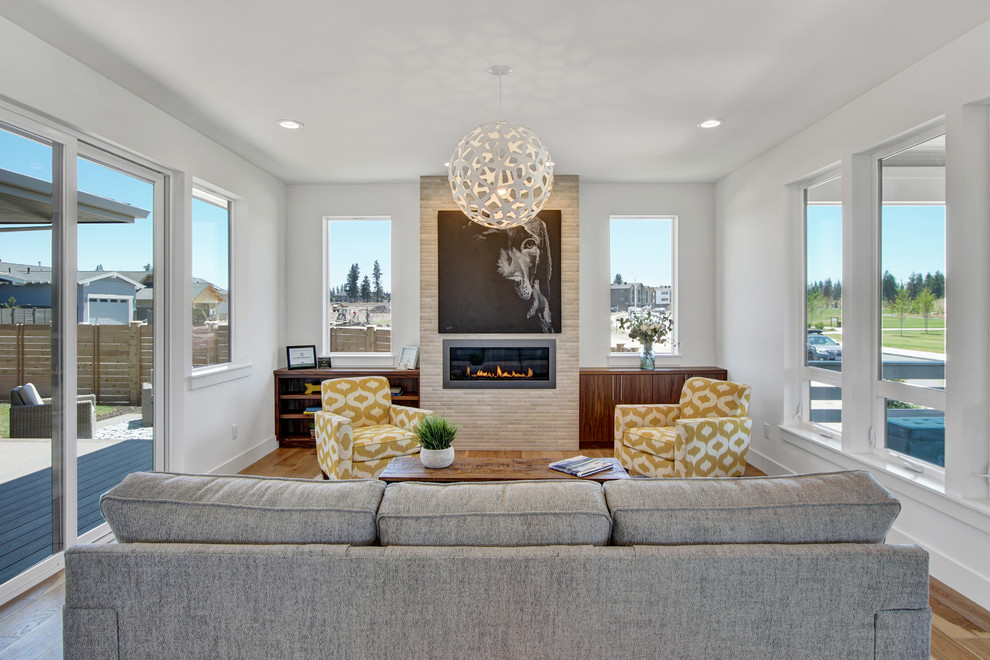 This is an example of a mid-sized contemporary formal open concept living room in Portland with white walls, light hardwood floors, a standard fireplace, a tile fireplace surround and no tv.