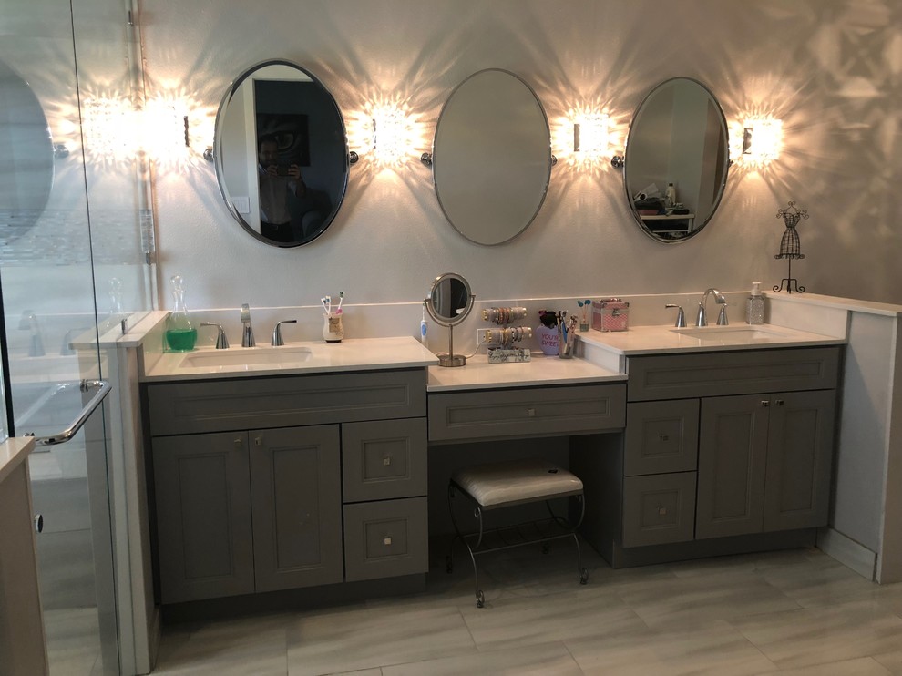 This is an example of a large modern master bathroom in Orlando with recessed-panel cabinets, grey cabinets, an alcove shower, grey walls, porcelain floors, an undermount sink, solid surface benchtops, grey floor, a hinged shower door and white benchtops.