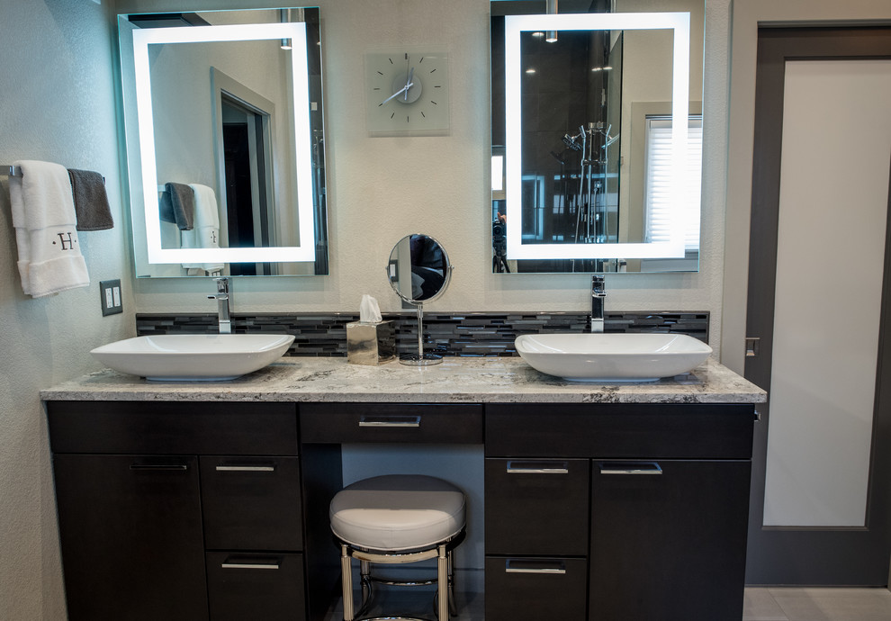 This is an example of a large modern master bathroom in Denver with flat-panel cabinets, dark wood cabinets, a freestanding tub, a double shower, a one-piece toilet, black tile, mosaic tile, grey walls, porcelain floors, a vessel sink and engineered quartz benchtops.