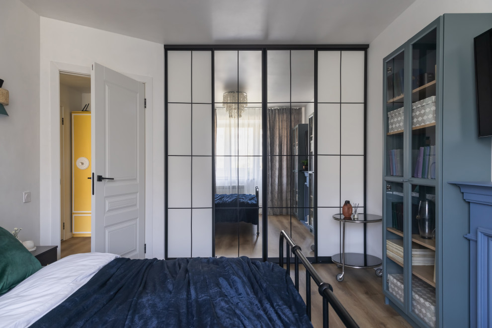 Cette image montre une chambre parentale design de taille moyenne avec un mur blanc, un sol en vinyl, une cheminée standard, un manteau de cheminée en bois et un sol marron.