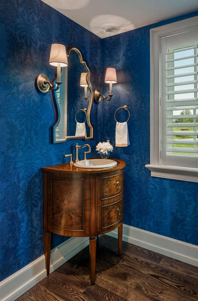 Photo of a traditional powder room in Philadelphia with furniture-like cabinets, medium wood cabinets, blue walls, medium hardwood floors, a drop-in sink and wood benchtops.