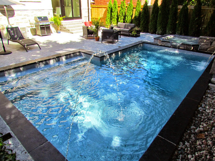 Design ideas for a small modern backyard custom-shaped lap pool in Toronto with a hot tub and natural stone pavers.