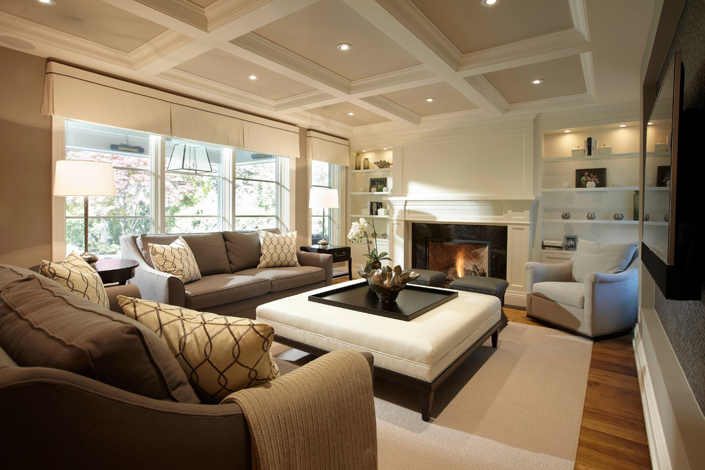 Design ideas for a large transitional open concept family room in Toronto with medium hardwood floors, a standard fireplace, a wall-mounted tv, grey walls and a wood fireplace surround.