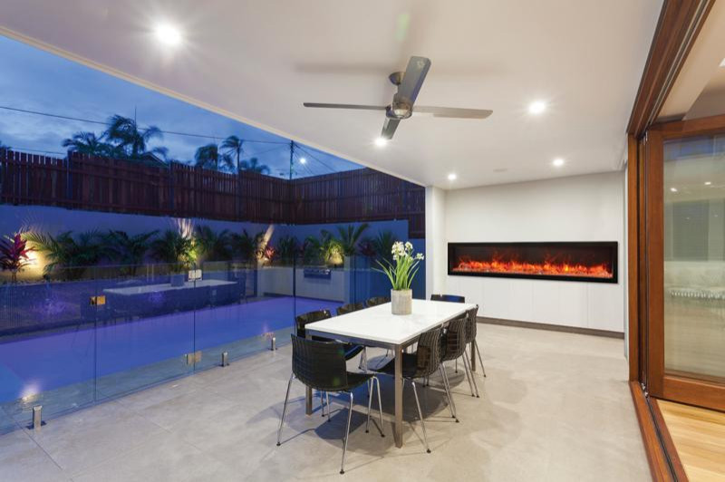 Photo of a mid-sized contemporary backyard patio in Miami with with fireplace and natural stone pavers.