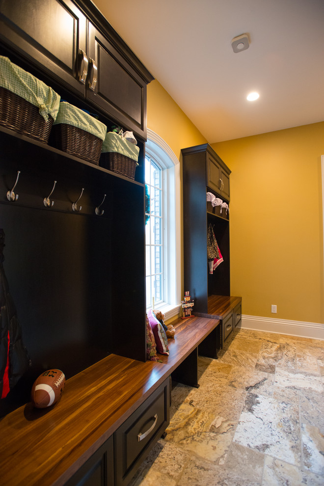 This is an example of a large traditional mudroom in Other with yellow walls, ceramic floors and beige floor.