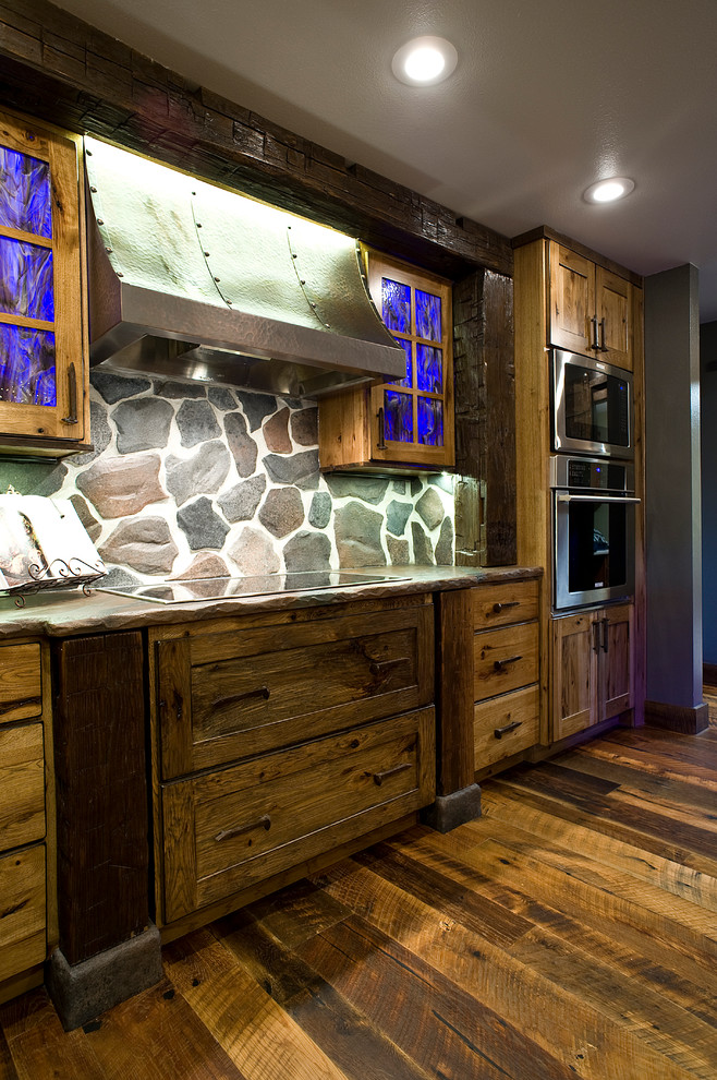 Eat-in kitchen - mid-sized rustic l-shaped medium tone wood floor eat-in kitchen idea with a farmhouse sink, shaker cabinets, distressed cabinets, concrete countertops, gray backsplash, stone slab backsplash, stainless steel appliances and an island