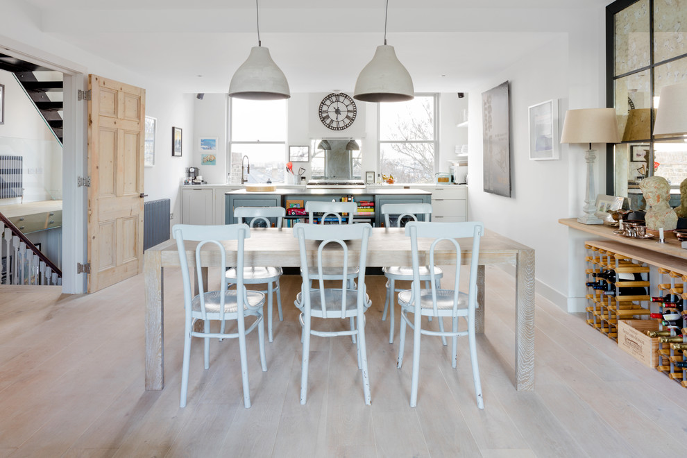 This is an example of a mid-sized beach style kitchen/dining combo in London with white walls, light hardwood floors and no fireplace.