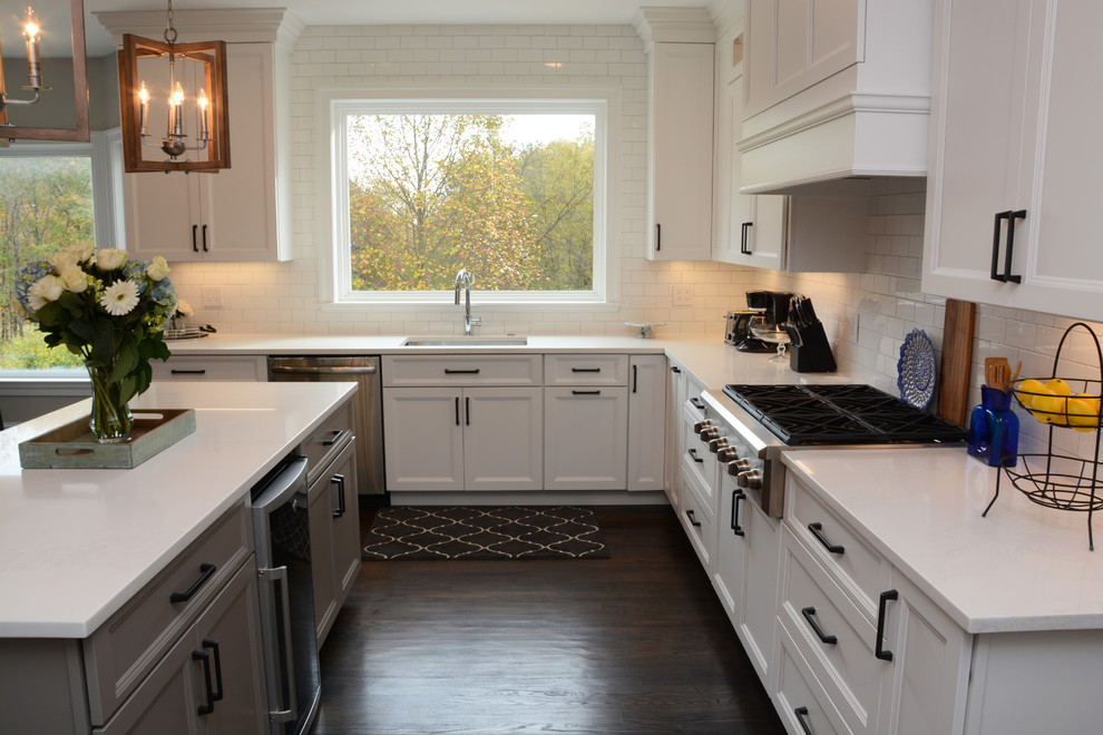 Inspiration for a large transitional l-shaped open plan kitchen in DC Metro with a single-bowl sink, recessed-panel cabinets, white cabinets, quartz benchtops, white splashback, subway tile splashback, stainless steel appliances, dark hardwood floors, with island and brown floor.