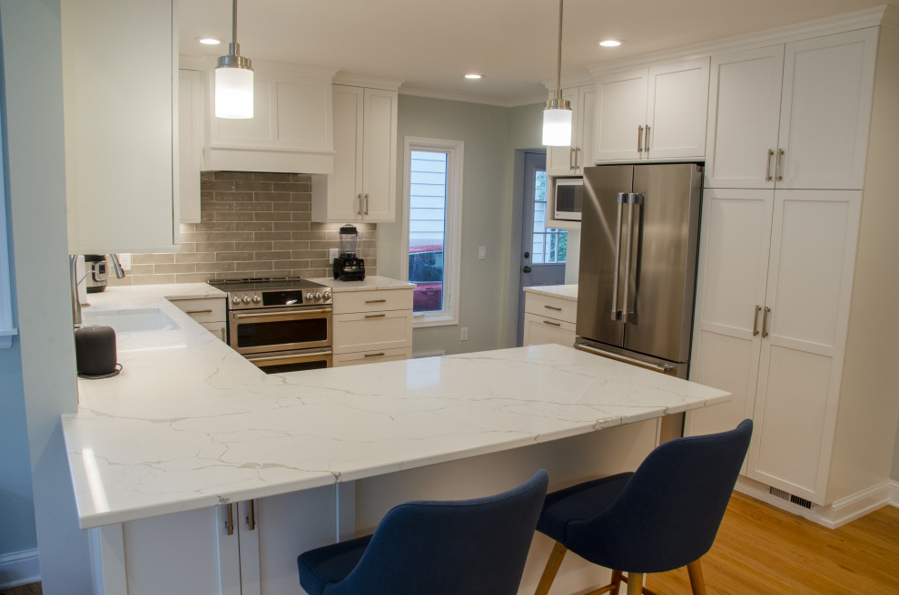 Inspiration for a large contemporary l-shaped dark wood floor and brown floor eat-in kitchen remodel in Minneapolis with an undermount sink, flat-panel cabinets, white cabinets, granite countertops, gray backsplash, subway tile backsplash, stainless steel appliances, a peninsula and white countertops