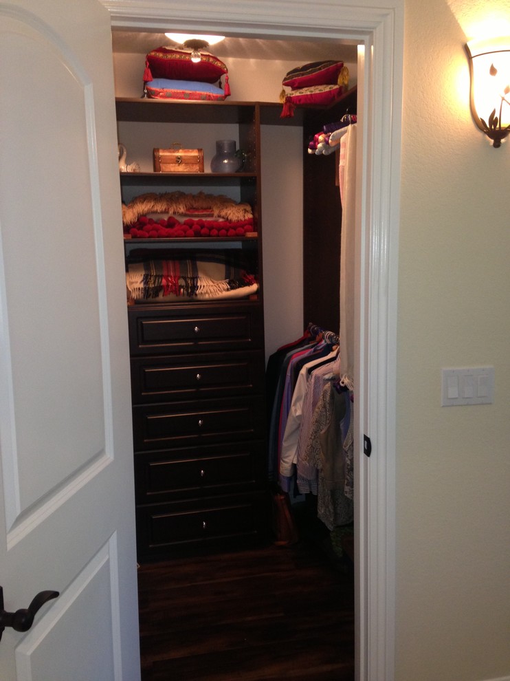 This is an example of a small transitional gender-neutral walk-in wardrobe in Los Angeles with recessed-panel cabinets, dark wood cabinets and dark hardwood floors.