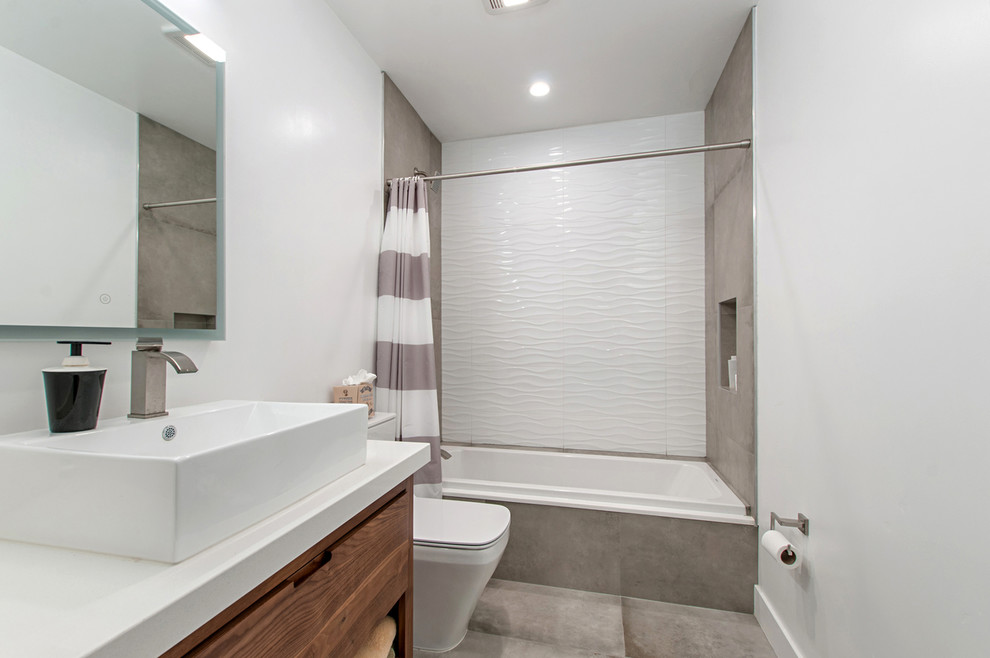 Photo of a large modern master wet room bathroom in San Diego with flat-panel cabinets, medium wood cabinets, a freestanding tub, gray tile, travertine, grey walls, cement tiles, a vessel sink, engineered quartz benchtops, grey floor and a hinged shower door.