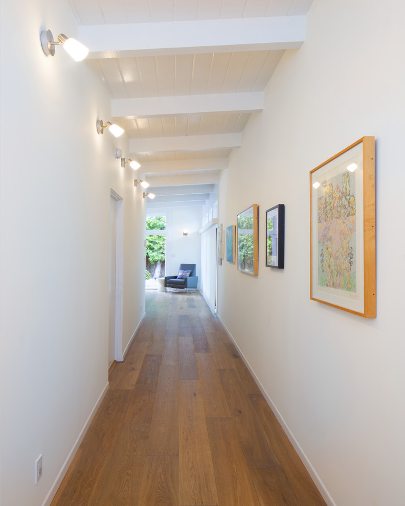 Design ideas for a mid-sized midcentury hallway in Los Angeles with white walls and medium hardwood floors.