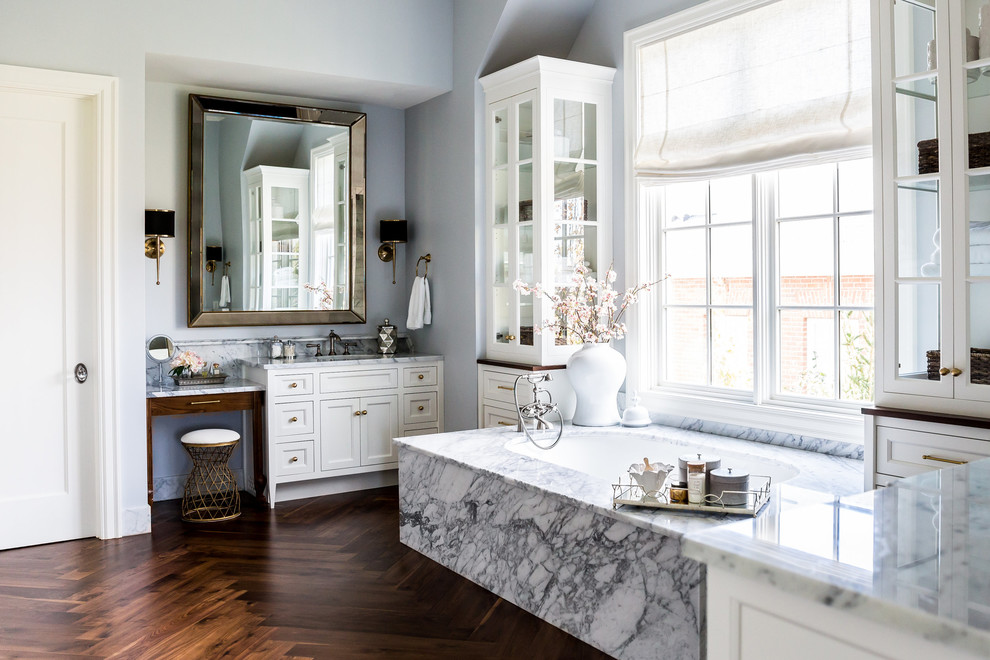 Large traditional master bathroom in Phoenix with shaker cabinets, white cabinets, gray tile, white tile, marble, grey walls, dark hardwood floors, marble benchtops, brown floor and an undermount tub.