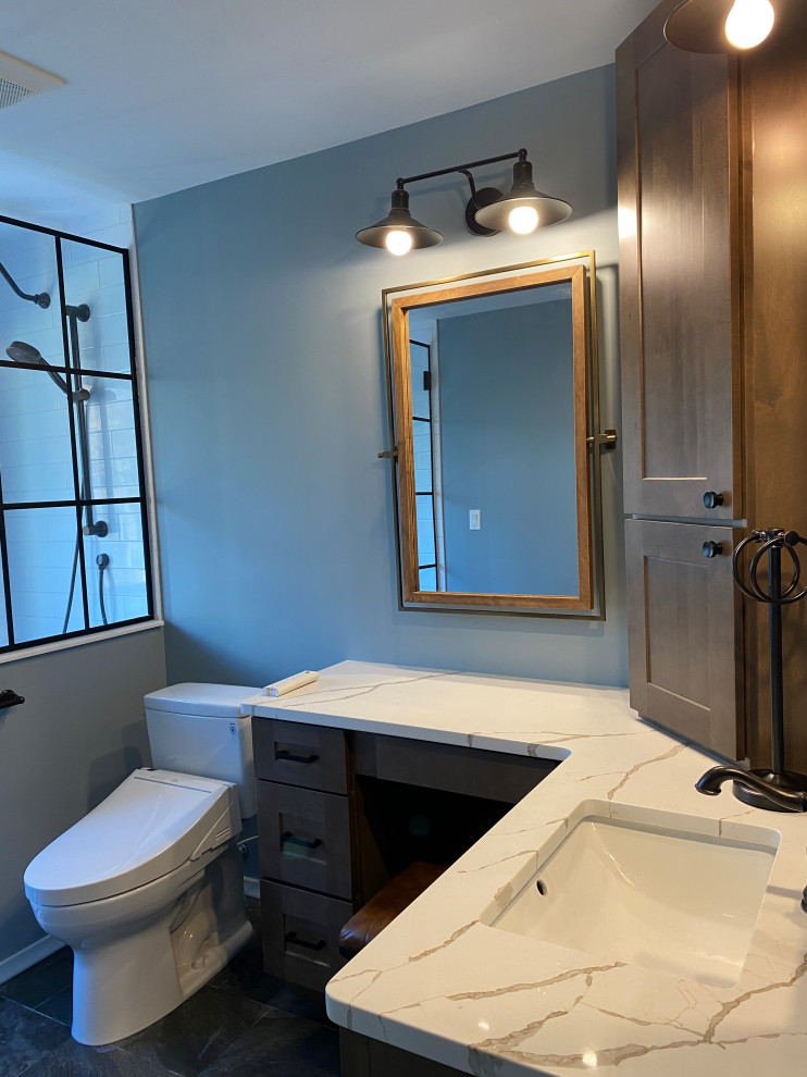 Small country ensuite bathroom in Detroit with shaker cabinets, medium wood cabinets, an alcove shower, a bidet, blue tiles, ceramic tiles, blue walls, ceramic flooring, engineered stone worktops, black floors, a hinged door, white worktops, a wall niche, a single sink and a built in vanity unit.