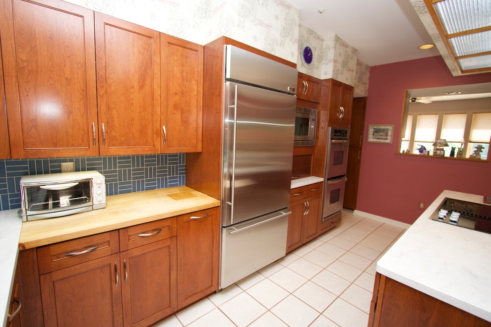 Open concept kitchen - transitional l-shaped ceramic tile open concept kitchen idea in Baltimore with an undermount sink, recessed-panel cabinets, medium tone wood cabinets, solid surface countertops, blue backsplash, ceramic backsplash, stainless steel appliances and an island