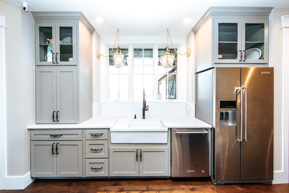Photo of a large country l-shaped eat-in kitchen in Austin with a farmhouse sink, shaker cabinets, blue cabinets, granite benchtops, white splashback, subway tile splashback, stainless steel appliances, bamboo floors, with island, brown floor and white benchtop.