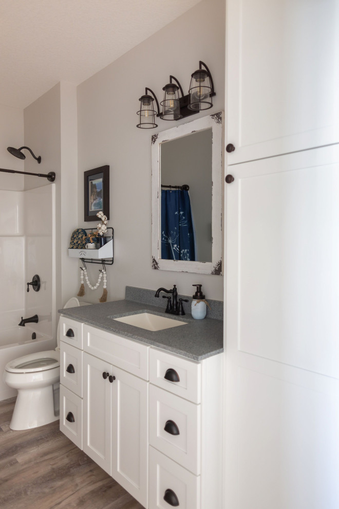 Lantlig inredning av ett mellanstort vit vitt en-suite badrum, med luckor med infälld panel, blå skåp, en kantlös dusch, en toalettstol med separat cisternkåpa, vita väggar, vinylgolv, ett integrerad handfat, bänkskiva i onyx, vitt golv och med dusch som är öppen