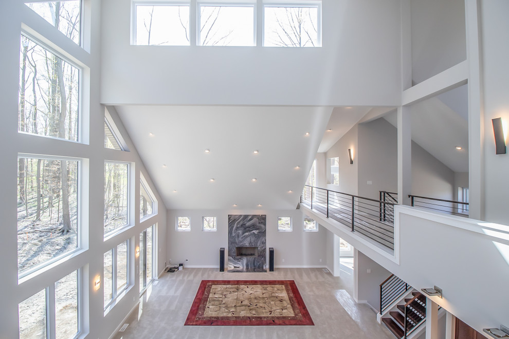 Photo of an expansive transitional open concept family room in Cleveland with grey walls, carpet, a standard fireplace, a stone fireplace surround and vaulted.