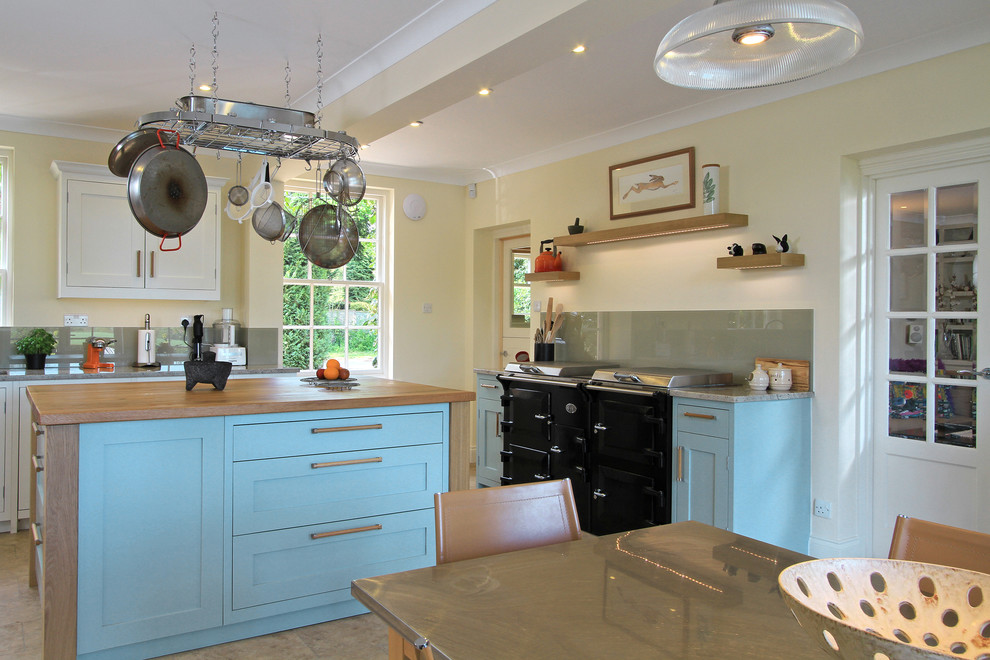 Inspiration for a traditional eat-in kitchen in Hampshire with wood benchtops, shaker cabinets, blue cabinets and black appliances.