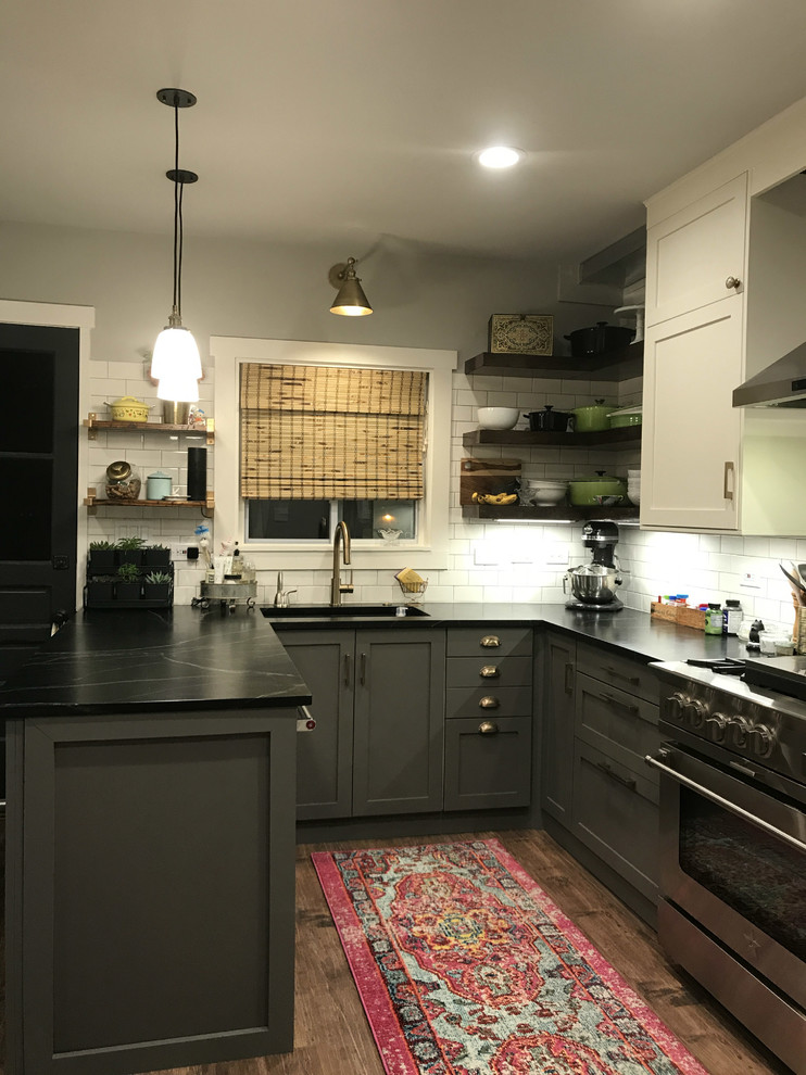 Mid-sized midcentury u-shaped eat-in kitchen in Other with an undermount sink, shaker cabinets, grey cabinets, white splashback, subway tile splashback, stainless steel appliances, dark hardwood floors, a peninsula, brown floor, black benchtop and soapstone benchtops.