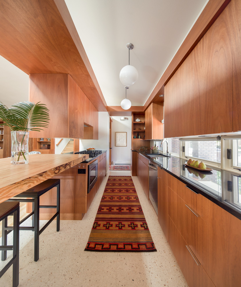 Inspiration for a small midcentury galley kitchen in Denver with flat-panel cabinets, medium wood cabinets, granite benchtops, terrazzo floors, a peninsula, black benchtop, an undermount sink and stainless steel appliances.