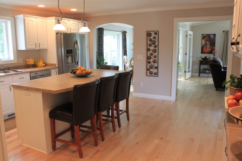 Example of a large minimalist galley light wood floor eat-in kitchen design with a drop-in sink, raised-panel cabinets, white cabinets, laminate countertops, stainless steel appliances and an island