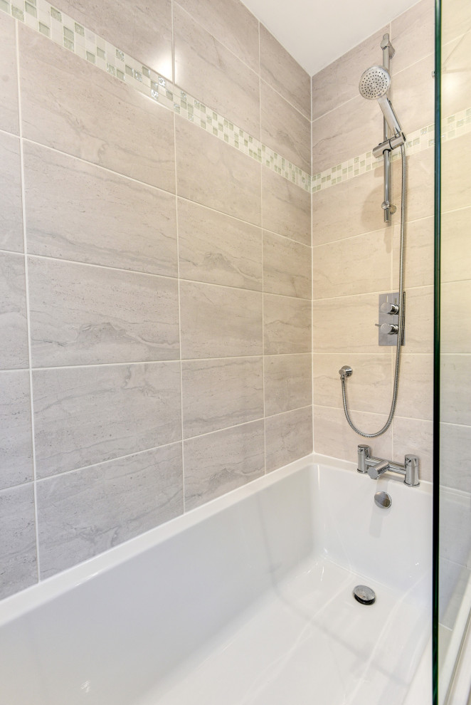 This is an example of a small modern grey and white family bathroom in Sussex with flat-panel cabinets, beige cabinets, a built-in bath, a shower/bath combination, grey tiles, ceramic tiles, grey walls, porcelain flooring, a built-in sink, laminate worktops, grey floors, a hinged door, grey worktops, a single sink and a built in vanity unit.