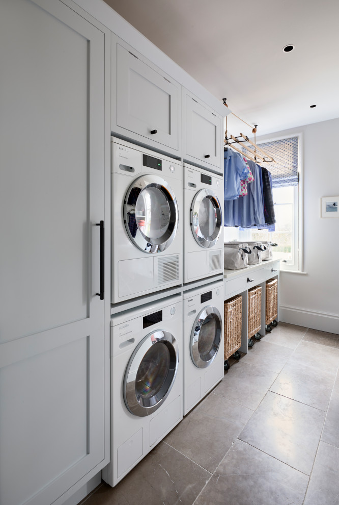 Large transitional galley laundry room in Hampshire with a drop-in sink, shaker cabinets, grey cabinets, marble benchtops, white splashback, marble splashback, light hardwood floors, beige floor and white benchtop.