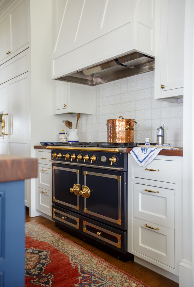 This is an example of a traditional galley separate kitchen in Jacksonville with beaded inset cabinets, white cabinets, wood benchtops, white splashback, porcelain splashback, coloured appliances, medium hardwood floors, with island, brown floor and brown benchtop.