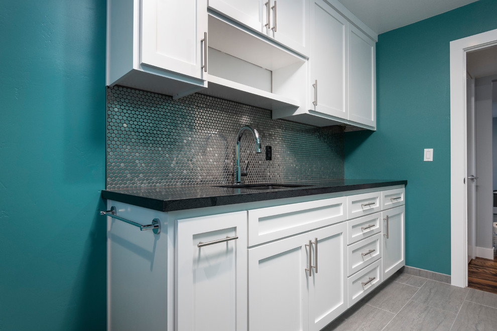Design ideas for a large contemporary l-shaped dedicated laundry room in San Francisco with an undermount sink, shaker cabinets, white cabinets, granite benchtops, porcelain floors, a side-by-side washer and dryer, grey floor, black benchtop and blue walls.