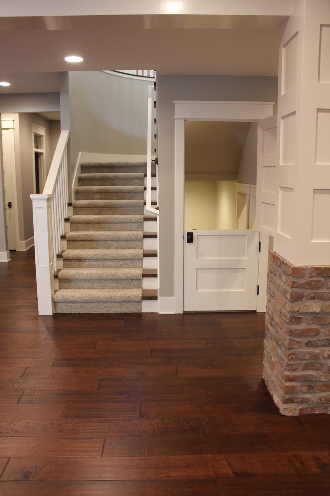 Photo of a large transitional walk-out basement in Salt Lake City with grey walls, a standard fireplace, a stone fireplace surround and dark hardwood floors.