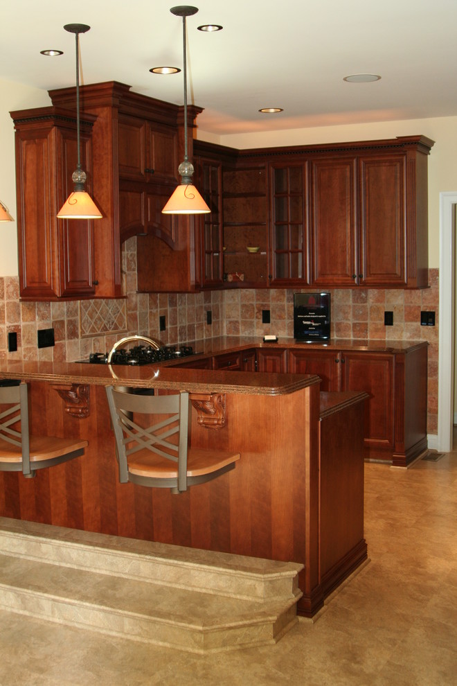 This is an example of a mid-sized traditional u-shaped separate kitchen in DC Metro with an undermount sink, raised-panel cabinets, dark wood cabinets, granite benchtops, beige splashback, ceramic splashback, black appliances, laminate floors, a peninsula, beige floor and brown benchtop.