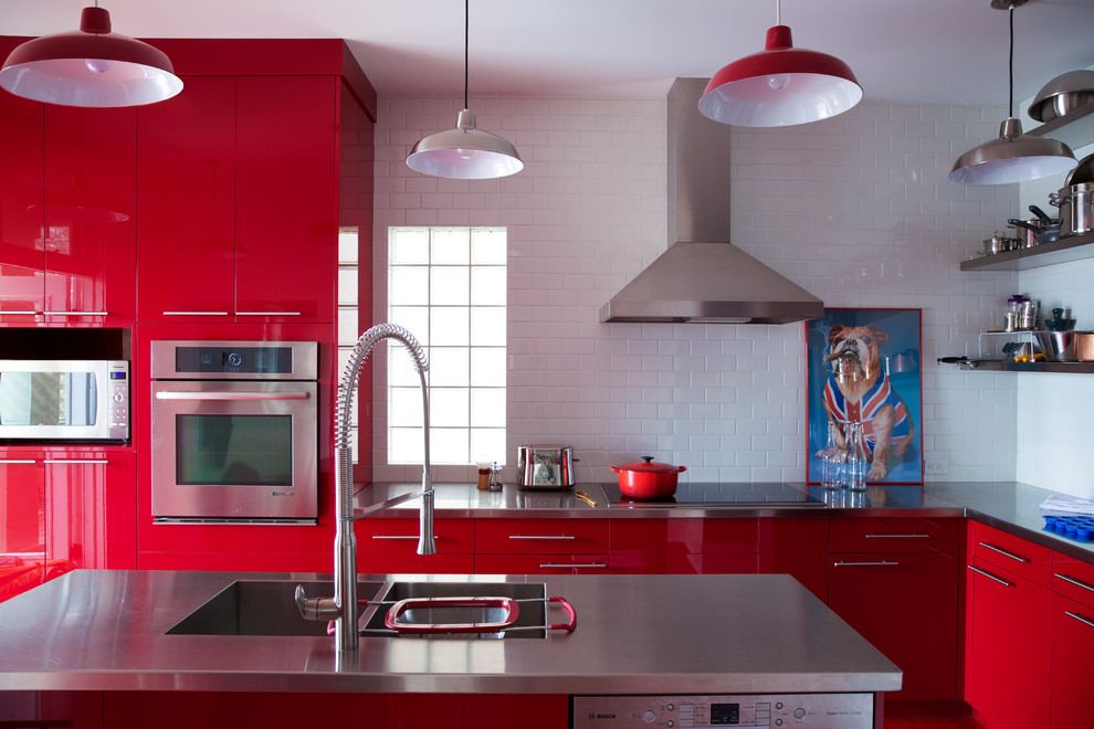 Design ideas for a large contemporary l-shaped kitchen in Calgary with a double-bowl sink, flat-panel cabinets, red cabinets, stainless steel benchtops, white splashback, subway tile splashback, stainless steel appliances and with island.