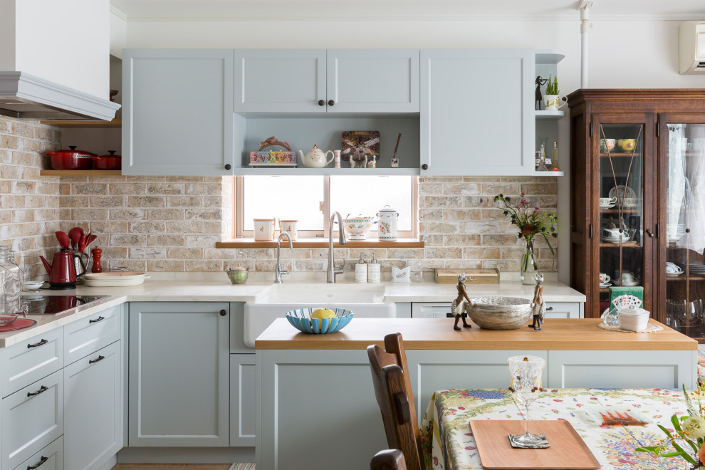 Inspiration for a traditional l-shaped eat-in kitchen in Tokyo with a farmhouse sink, recessed-panel cabinets, grey cabinets, beige splashback, brick splashback, with island and white benchtop.