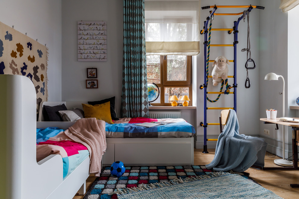 This is an example of a contemporary gender-neutral kids' bedroom for kids 4-10 years old in Other with white walls and light hardwood floors.