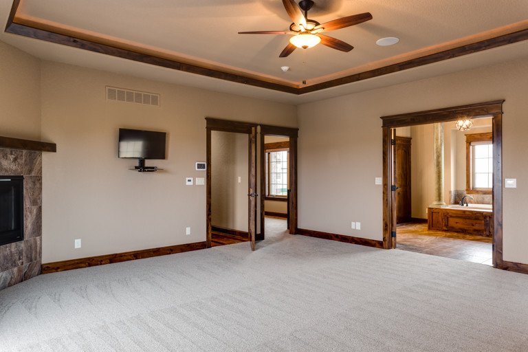 Inspiration for a large rustic master carpeted bedroom remodel with beige walls, a standard fireplace and a tile fireplace