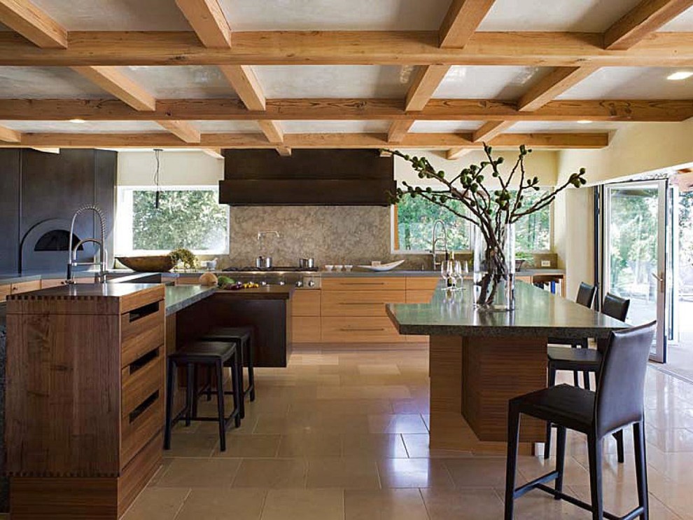 This is an example of an arts and crafts kitchen in Seattle with flat-panel cabinets, light wood cabinets, stone slab splashback, stainless steel appliances, travertine floors, multiple islands and beige floor.