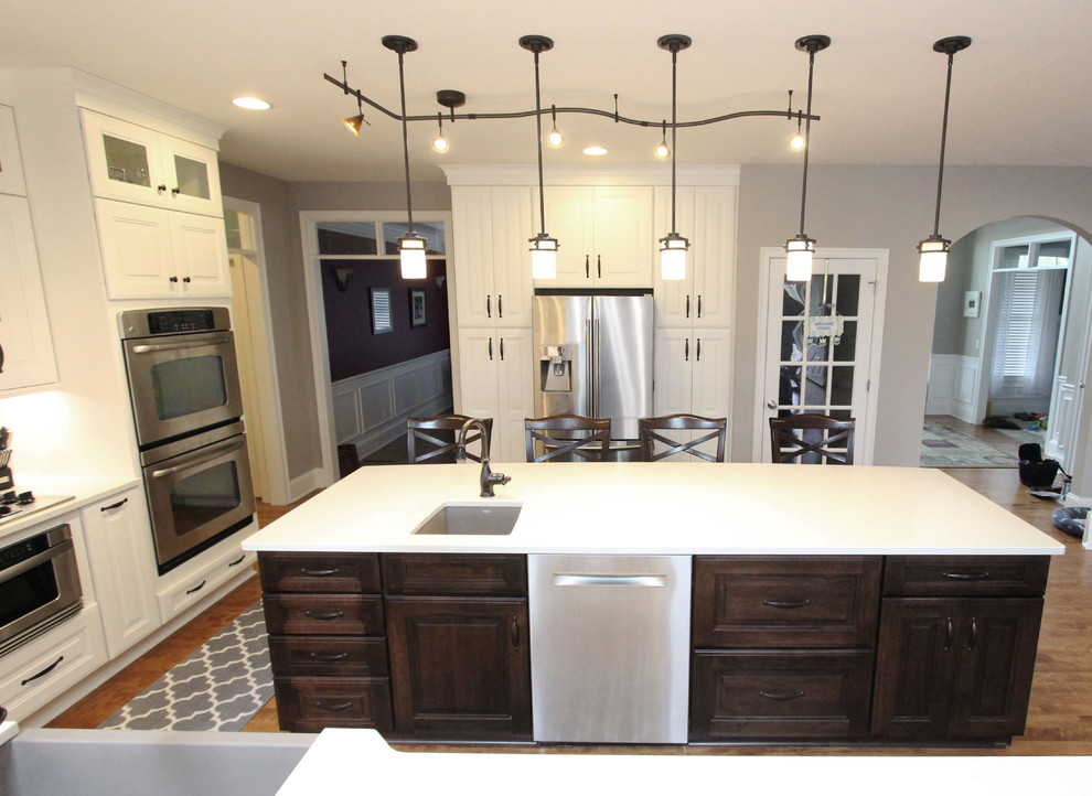 Inspiration for a large transitional l-shaped eat-in kitchen with a farmhouse sink, raised-panel cabinets, white cabinets, quartz benchtops, grey splashback, mosaic tile splashback, stainless steel appliances, with island and white benchtop.