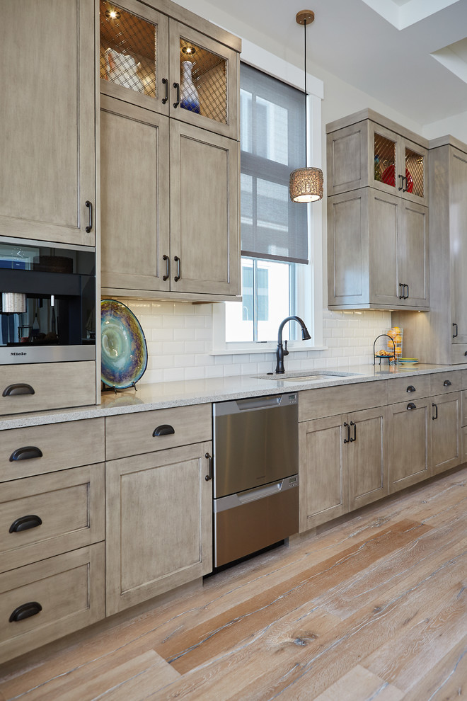 This is an example of a mid-sized traditional l-shaped eat-in kitchen in Grand Rapids with an undermount sink, shaker cabinets, light wood cabinets, granite benchtops, white splashback, subway tile splashback, panelled appliances, light hardwood floors and with island.