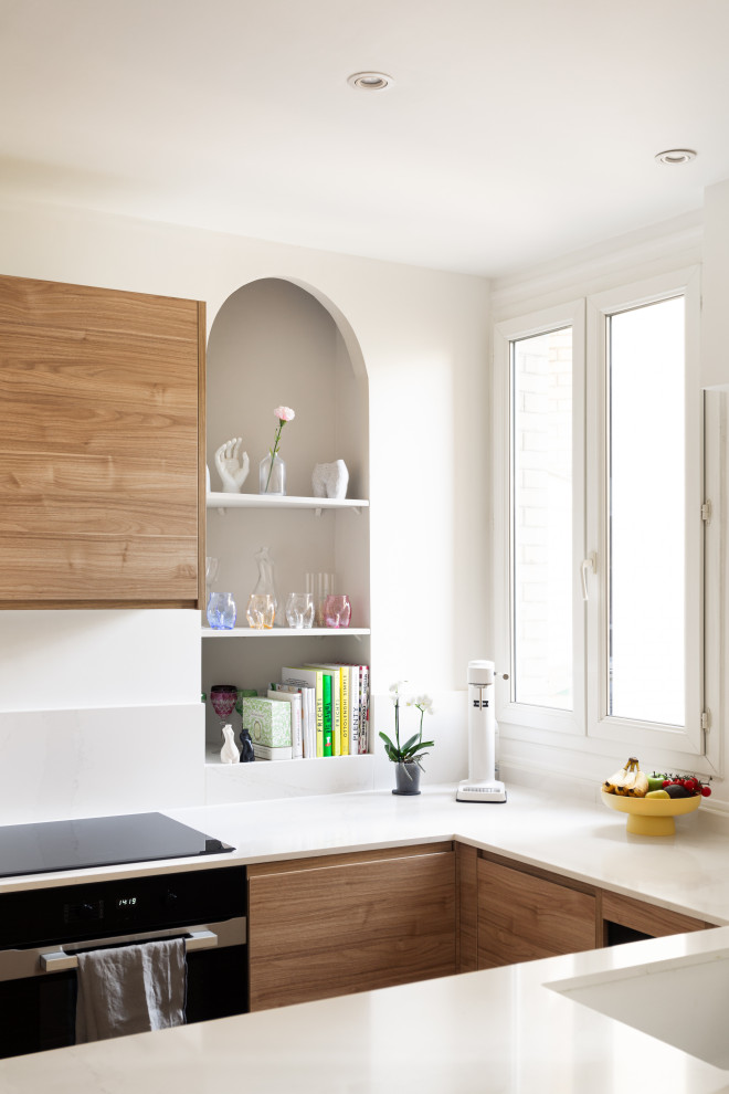 Bild på ett mellanstort funkis vit vitt kök, med en integrerad diskho, luckor med profilerade fronter, skåp i ljust trä, bänkskiva i kvartsit, vitt stänkskydd, stänkskydd i marmor, svarta vitvaror, en köksö och beiget golv
