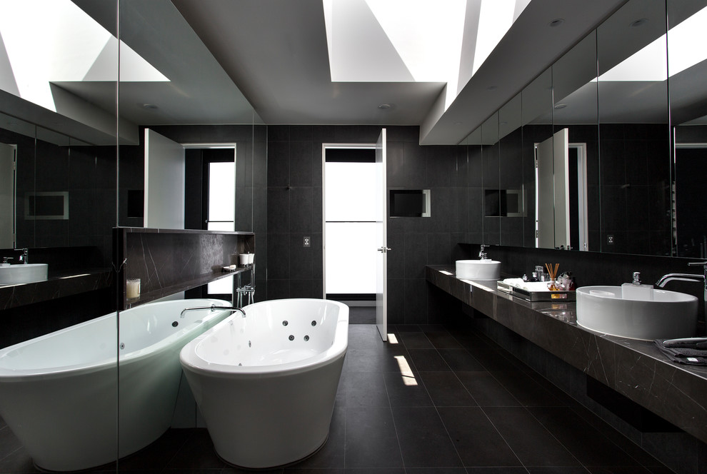 Exemple d'une grande salle de bain principale tendance avec une baignoire indépendante, un carrelage noir, du carrelage en marbre, un mur noir, un sol en carrelage de porcelaine, un plan de toilette en marbre et un sol noir.