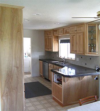 Galley white floor kitchen photo with raised-panel cabinets, stainless steel appliances, a peninsula and gray countertops