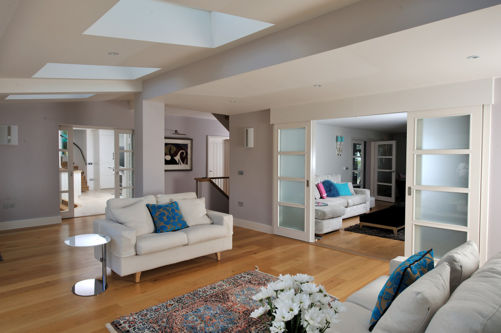 Photo of a large contemporary open plan living room in Cornwall with white walls, medium hardwood flooring and a vaulted ceiling.