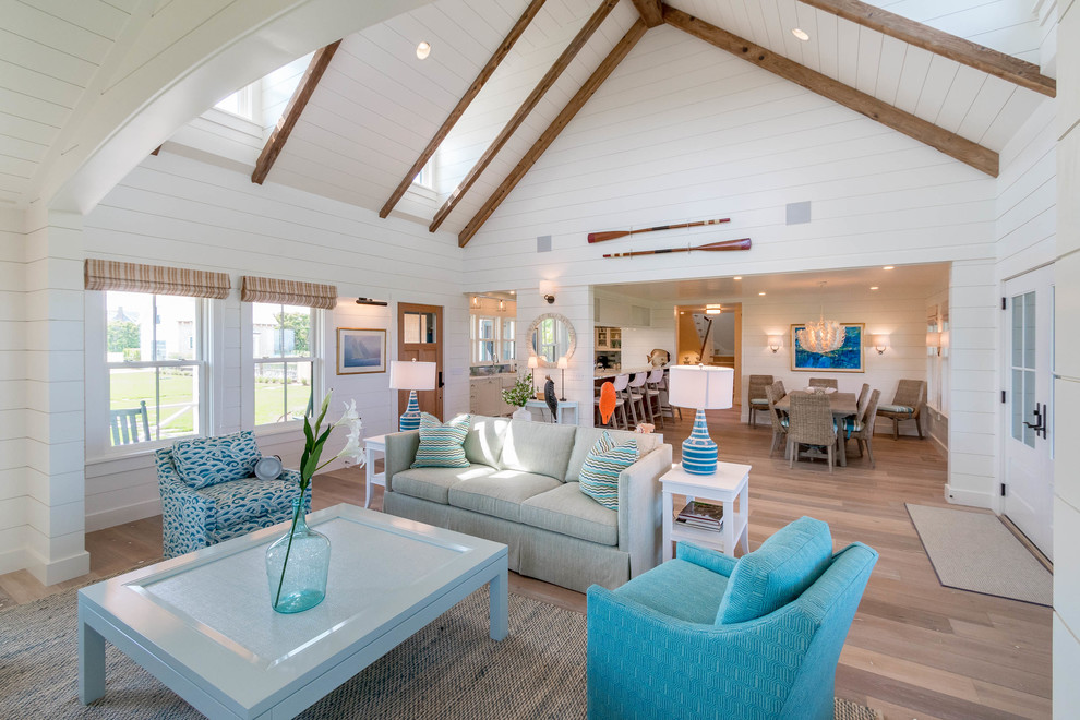 Large beach style open concept living room in Boston with brown walls, light hardwood floors, a standard fireplace, a metal fireplace surround, a wall-mounted tv, brown floor, exposed beam and wood walls.