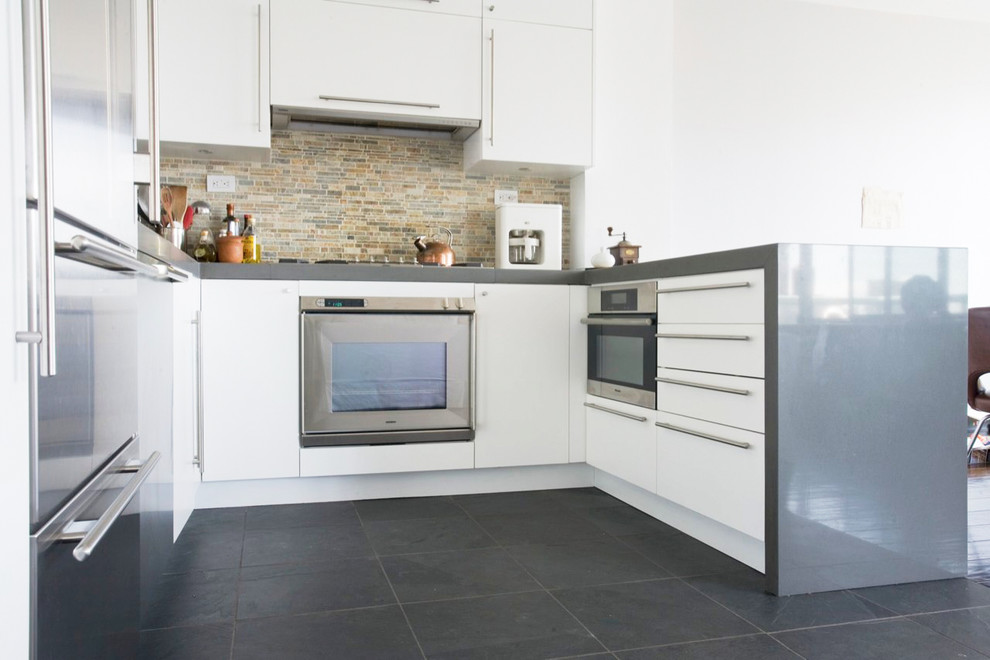 Mid-sized modern u-shaped eat-in kitchen in New York with an undermount sink, flat-panel cabinets, white cabinets, quartz benchtops, multi-coloured splashback, matchstick tile splashback, stainless steel appliances, slate floors, a peninsula, black floor and grey benchtop.