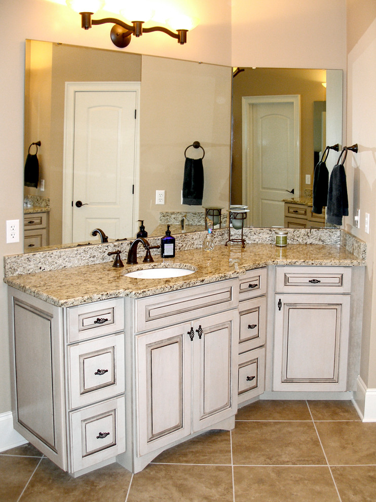 This is an example of a large traditional bathroom in Charlotte with an undermount sink, raised-panel cabinets, white cabinets, granite benchtops, a drop-in tub, a corner shower, a two-piece toilet, beige tile, porcelain tile, beige walls and porcelain floors.