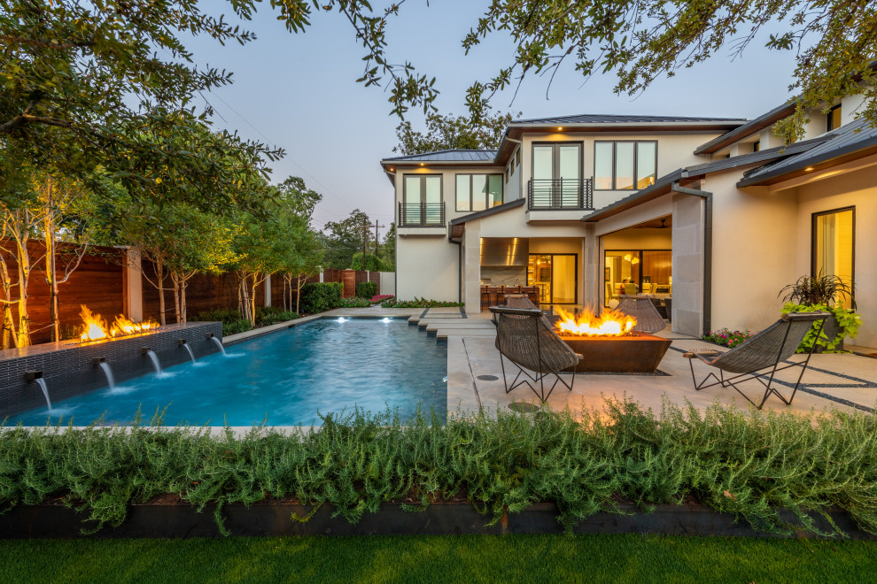 Inspiration for a large contemporary backyard rectangular lap pool in Dallas with a water feature and concrete slab.