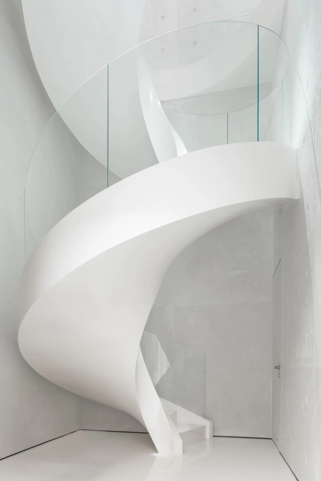 Immagine di una scala curva minimalista di medie dimensioni con pedata in marmo e parapetto in vetro