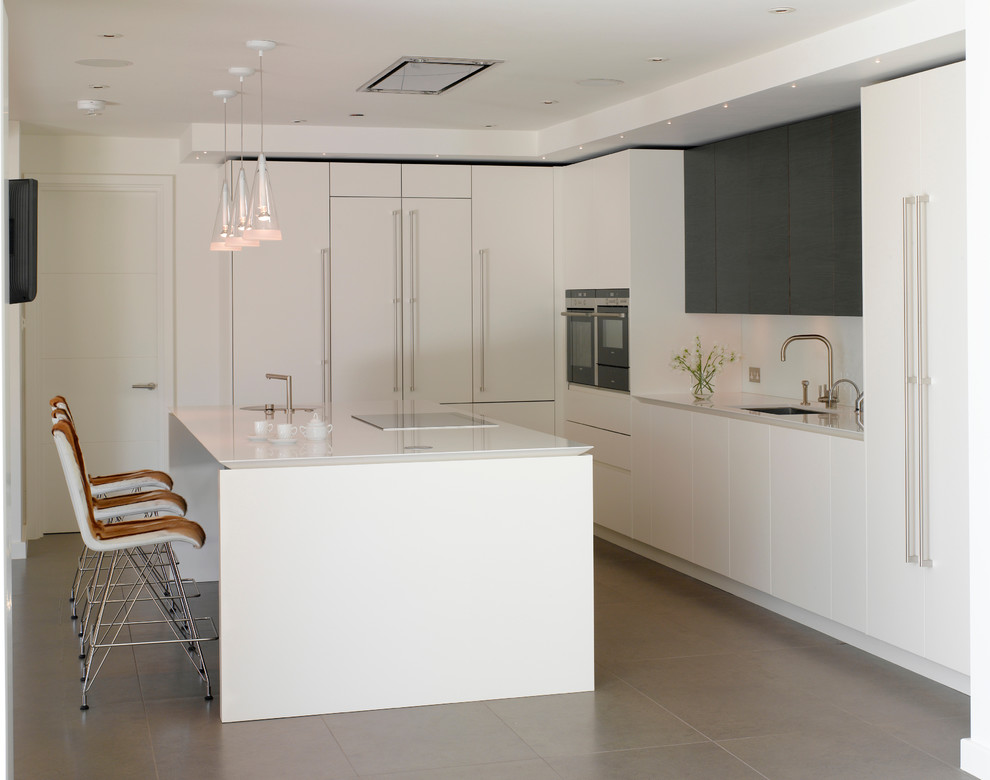 This is an example of a large contemporary open plan kitchen in London with an undermount sink, flat-panel cabinets, white cabinets, solid surface benchtops and with island.