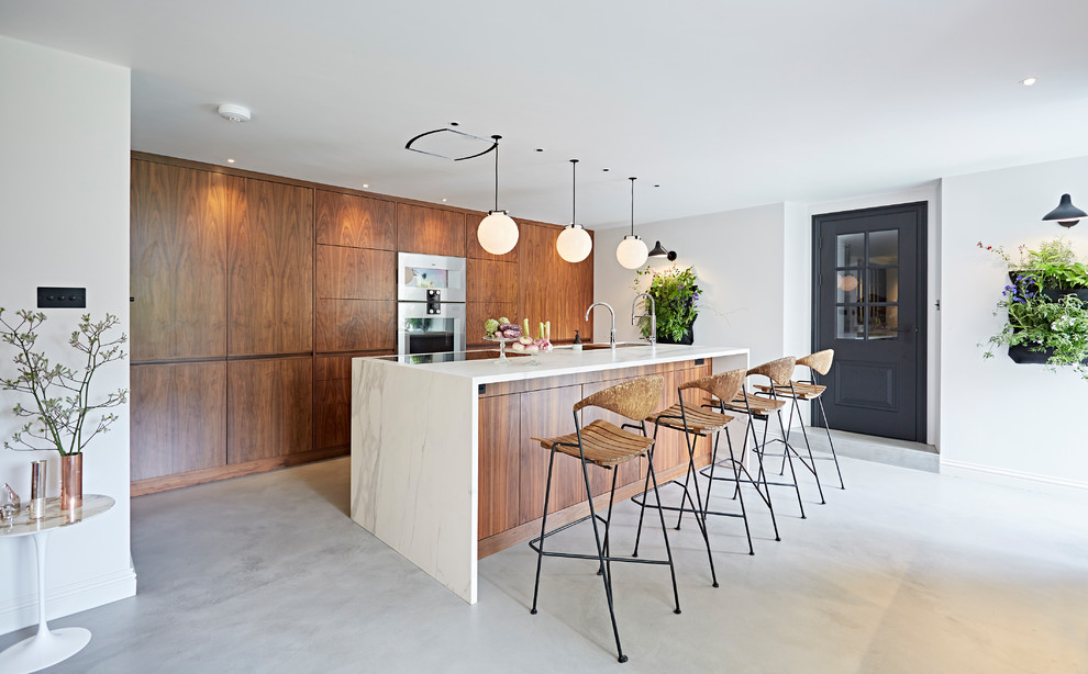 This is an example of a mid-sized midcentury single-wall kitchen in Devon with flat-panel cabinets, dark wood cabinets, marble benchtops, panelled appliances, concrete floors, a peninsula and grey floor.